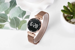 Detalle del reloj LED oro rosa con correa magnética y cristal tallado en mesa blanca