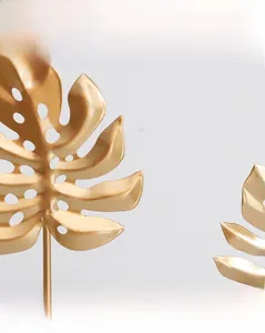 Detailed macro shot of the golden Monstera leaf sculpture showing matte iron texture