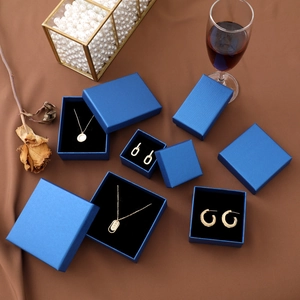 Elegant peacock blue jewelry box set with golden necklace and earrings on brown fabric