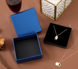 Deep blue jewelry gift box with gold pendant necklaces on brown textured background