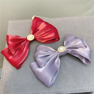 Detailed view of large dark red and lavender satin hair bows with pearl center ornaments