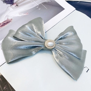 Detail of a dusty blue satin double bow hair clip with central pearl and rhinestones