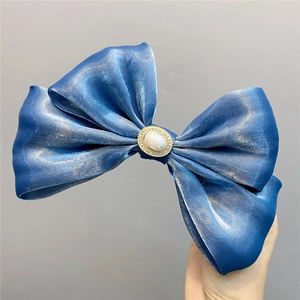 Detail of blue silk double bow hair clip with central oval pearl and crystal rhinestones