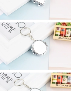 Close-up of a silver mini folding mirror keychain on a blue background with decor