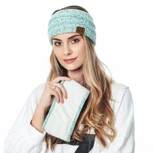 Detail view of light green knitted winter headband featuring a brown leather MOK label
