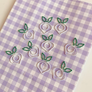 Gros plan de trombones en forme de carottes blanches et vertes sur fond à carreaux violets