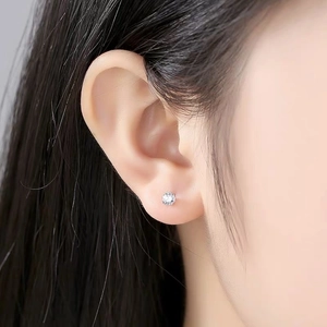 Macro shot of minimalist S999 sterling silver stud earring with a four-claw zircon on model