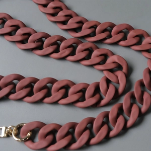 Detail of matte brick red resin chunky chain with golden round carabiner clasp