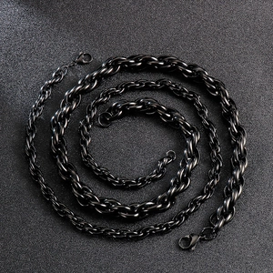 Detail of two black stainless steel twisted chains with lobster clasps on a dark surface