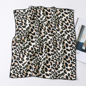 Detail of square silk scarf showing leopard print pattern and black stitched edges