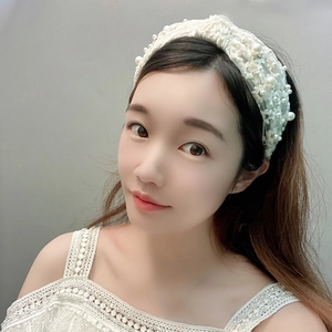 Elegant white lace headband with floral embroidery and pearls shown on a model