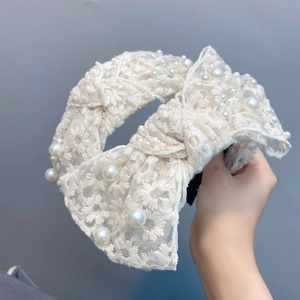 Detailed view of white lace headband featuring intricate flower embroidery and pearls