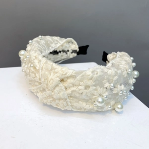Detailed close-up of lace headband with daisy embroidery and elegant pearl accents