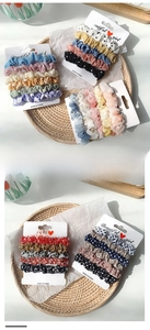 Détail d'un lot de chouchous en satin avec motifs floraux sur cartes de support