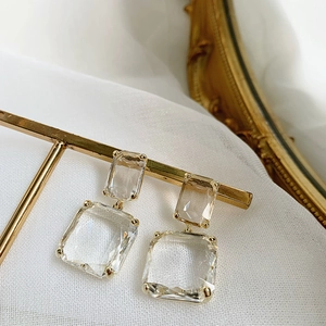 Detail of gold geometric earrings with clear crystals on a metal display stand