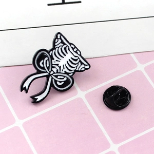 Detailed macro view of punk skull ribcage enamel pin with bow and black butterfly clasp