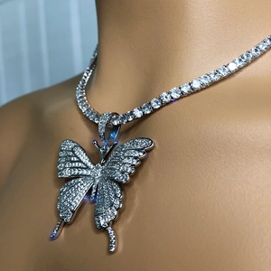Detail of iced out butterfly pendant with clear crystals on a silver tennis chain