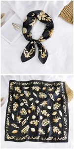 Detail of square silk scarf showing black fabric with elegant golden leaf print