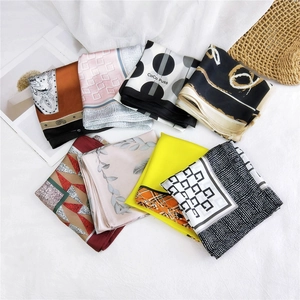 Various silk square scarves with geometric and floral prints on a white background