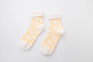 Detailed view of yellow and white heart pattern coral fleece socks with fuzzy cuffs