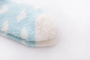 Detailed macro view of soft light blue coral fleece socks featuring white cloud patterns