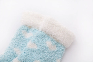 Close-up of blue coral fleece socks with white cloud patterns and soft plush cuffs