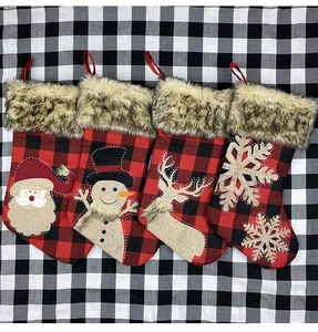 Détail de quatre chaussettes de Noël à carreaux avec bordure en fourrure et écussons