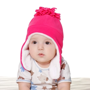Detail of pink fleece baby earflap hat with white plush lining and tassel for winter warmth