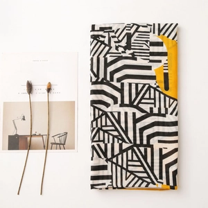Detail of thin cotton linen scarf with black-white geometric patterns and yellow accents