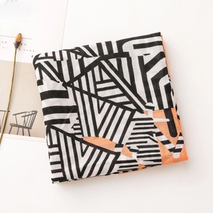 Flat lay of geometric pattern linen shawl with orange and black stripes on white surface
