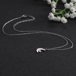 Detailed view of silver star and moon pendant necklace on a textured black surface