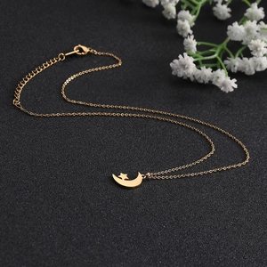 Detail of gold star and moon pendant necklace with delicate chain on black background