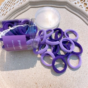 Jar of high-elastic seamless hair ties in various purple shades on a minimalist tray