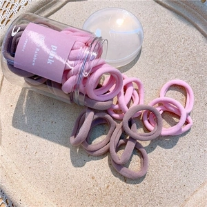Close-up of colorful seamless elastic hair ties spilling from a plastic storage jar