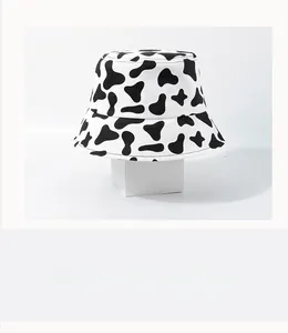 Detail of black and white cow print bucket hat on a white minimalist display stand