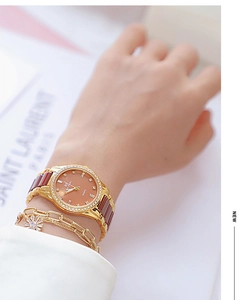 Close-up of elegant women's ceramic brown watch with crystal bezel and gold bracelets
