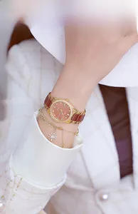 Close-up of elegant rose gold ceramic watch with brown dial and floral charm bracelet
