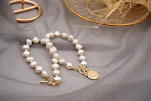 Detail of baroque pearl bracelet with golden OT clasp and vintage coin pendant