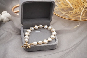 Detailed shot of baroque freshwater pearl bracelet with gold T-bar clasp in velvet box