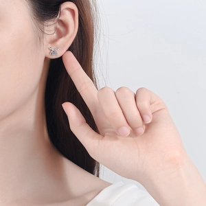 Elegant S925 sterling silver bow stud earrings with blue moissanite stones on a female model