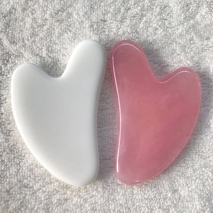 Resin heart-shaped Gua Sha scraping tools in white and pink colors on a white towel