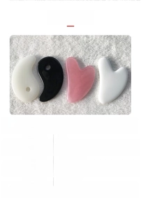 Detail showing heart and comma shaped resin massage tools on white towel background
