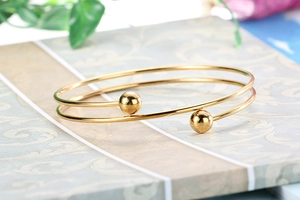 Close-up of golden double-layer beaded stainless steel cuff bracelet on vintage paper