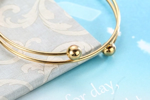 Macro detail of golden stainless steel double-line bangle with polished round beads