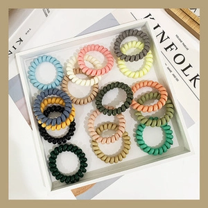 Colorful spiral telephone cord hair ties in a minimalist white tray for hair styling