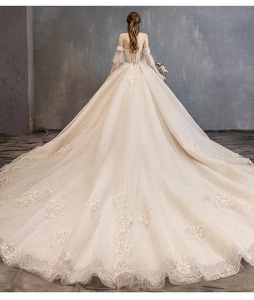 Detail of elegant champagne wedding dress featuring lace embroidery and long royal train