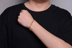 Close-up of gold Cuban link bracelet featuring rectangular clear zircons on wrist
