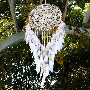 Macro shot of bohemian white dream catcher with handmade lace and natural feathers