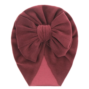 Detail view of burgundy velvet baby turban hat with a large decorative soft bow
