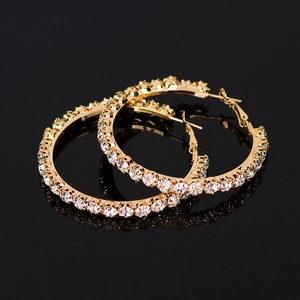Exaggerated gold hoop earrings with sparkling rhinestones on a black background